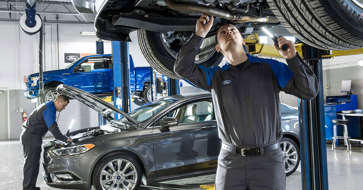 Two Ford Service crew members working on Ford vehicles in a garage.