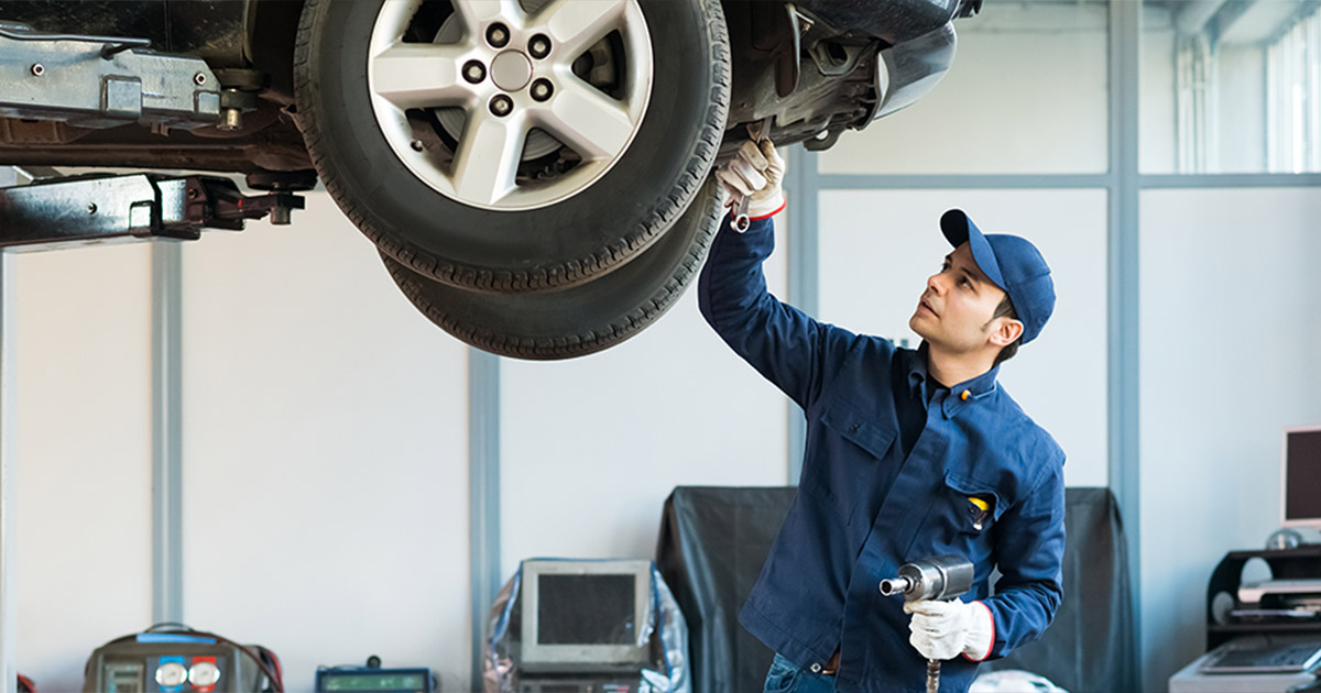 Service technician working underneath a vehicle.