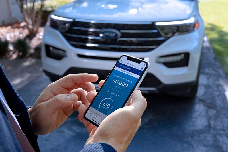 A person operating Ford App in front of Ford car