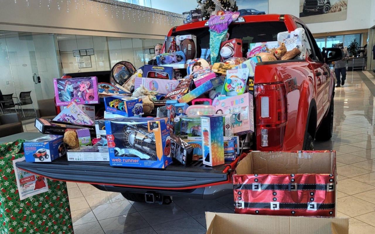 Red pickup truck bed filled with Christmas toys for donation.